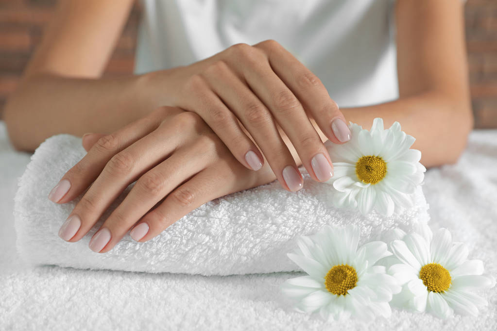 Femme aux mains lisses et fleurs sur serviette, gros plan. Traitement spa
 - Photo, image