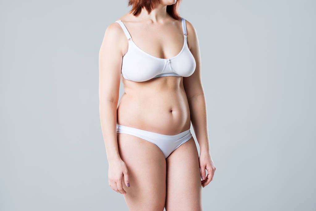 Γυναίκα με παχιά πλαδαρή κοιλιά, υπέρβαρο γυναικείο σώμα σε γκρι φόντο - Φωτογραφία, εικόνα