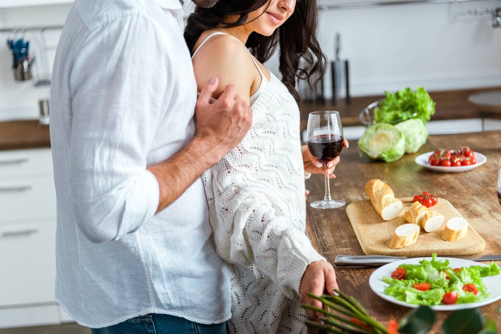 gedeeltelijke weergave van gepassioneerde man aanraken van de vrouw in de keuken - Foto, afbeelding