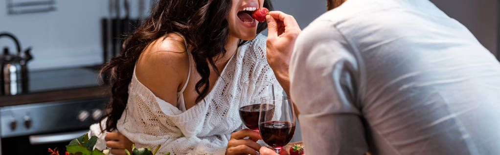 vista cortada de homem alimentando mulher com morango, tiro panorâmico
 - Foto, Imagem