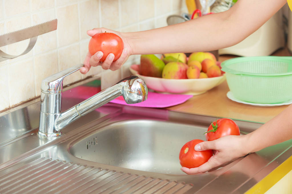Kobieta myje świeże warzywa w kuchni - Zdjęcie, obraz
