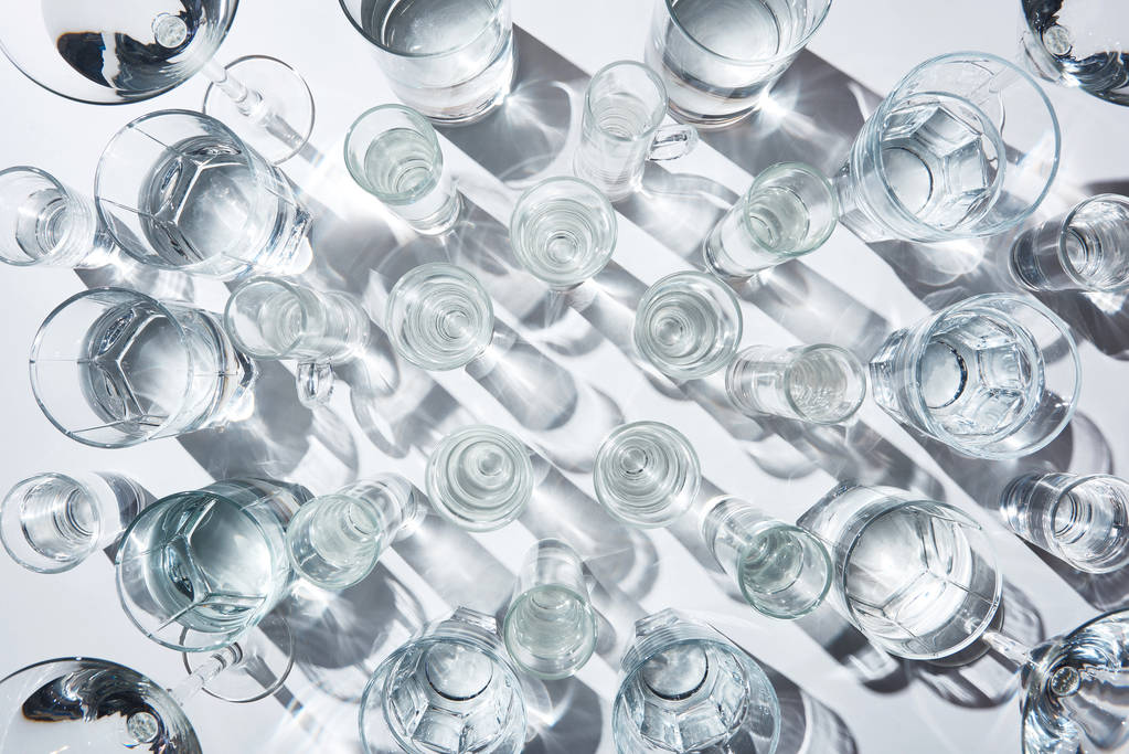 vista superior de vasos con agua pura y sombras sobre superficie blanca
 - Foto, imagen