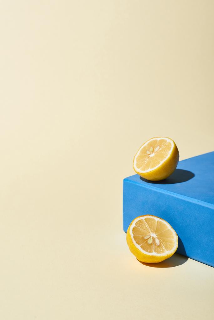 φωτεινό μισό λεμόνι και μπλε κύβο σε μπεζ φόντο - Φωτογραφία, εικόνα