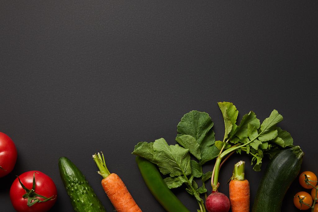 Κορυφαία θέα των ακατέργαστων θρεπτικών νόστιμα λαχανικά με πράσινα φύλλα σε μαύρο φόντο με χώρο αντιγραφής - Φωτογραφία, εικόνα