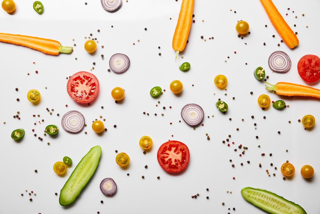 vista superior de verduras en rodajas orgánicas y pimienta negra sobre fondo blanco
 - Foto, imagen
