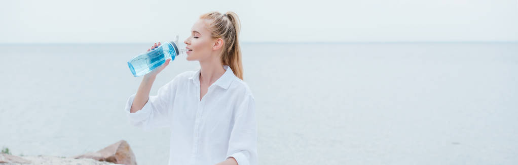 panoramic shot of happy blonde woman drinking water  - Photo, Image