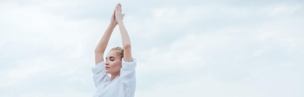plan panoramique de fille attrayante avec les yeux fermés pratiquant le yoga et debout avec les mains priantes
  - Photo, image
