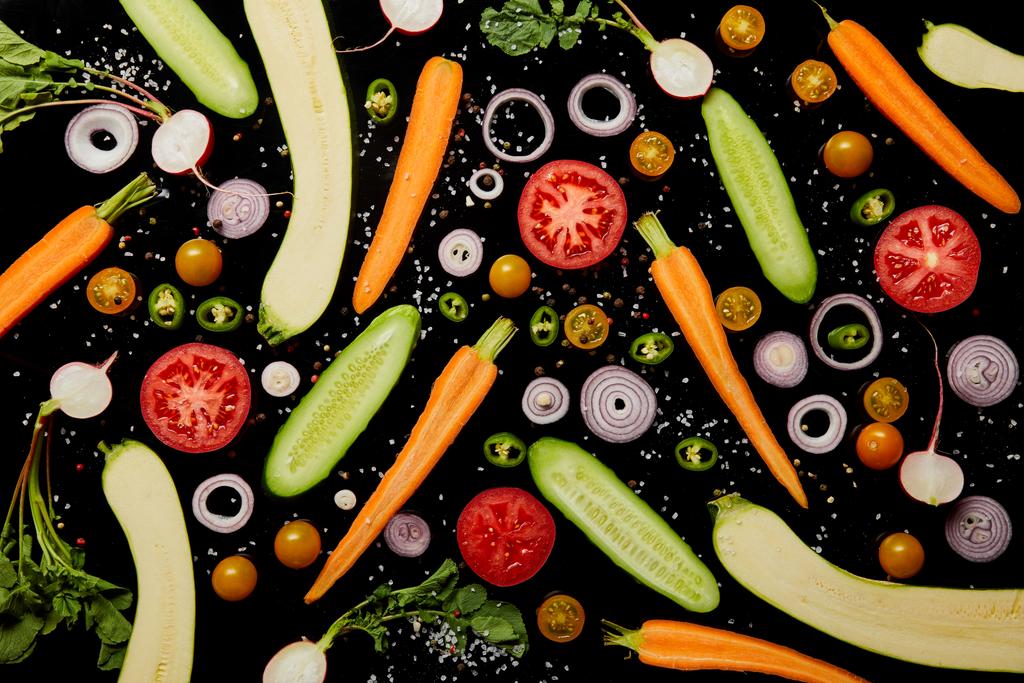 Draufsicht auf frische Gemüsescheiben mit Salz isoliert auf schwarz, Hintergrundmuster - Foto, Bild