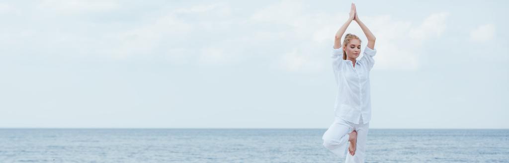 panoramische foto van blonde vrouw met gesloten ogen die yoga beoefenen  - Foto, afbeelding