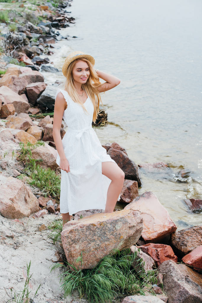 щаслива і красива блондинка посміхається, стоячи біля моря
  - Фото, зображення