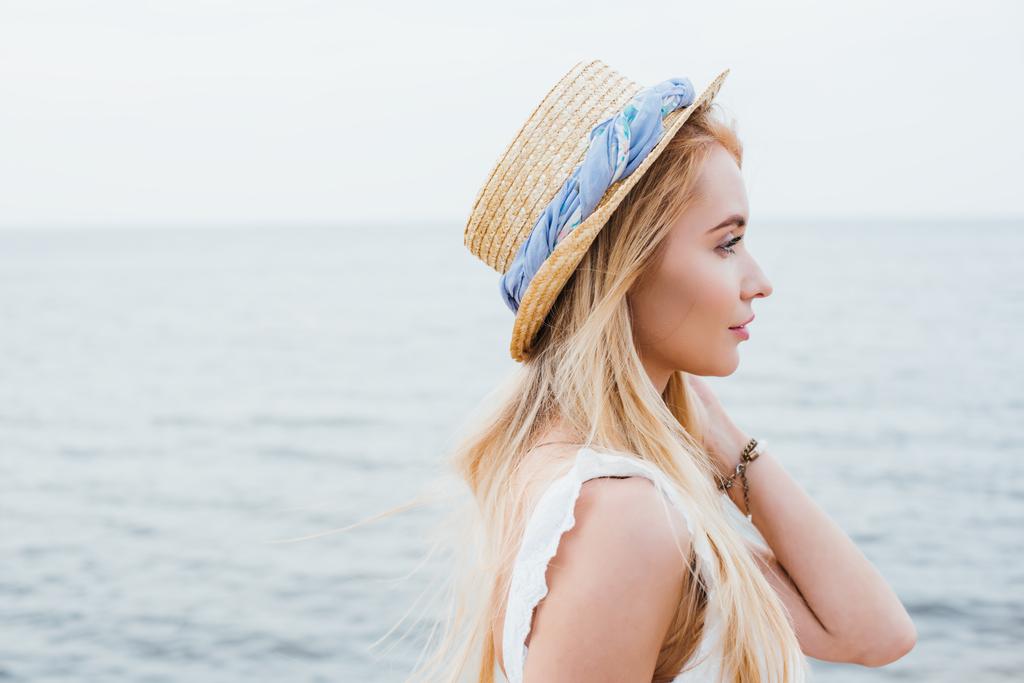 vue latérale de jolie jeune femme blonde en chapeau de paille près de la mer
  - Photo, image