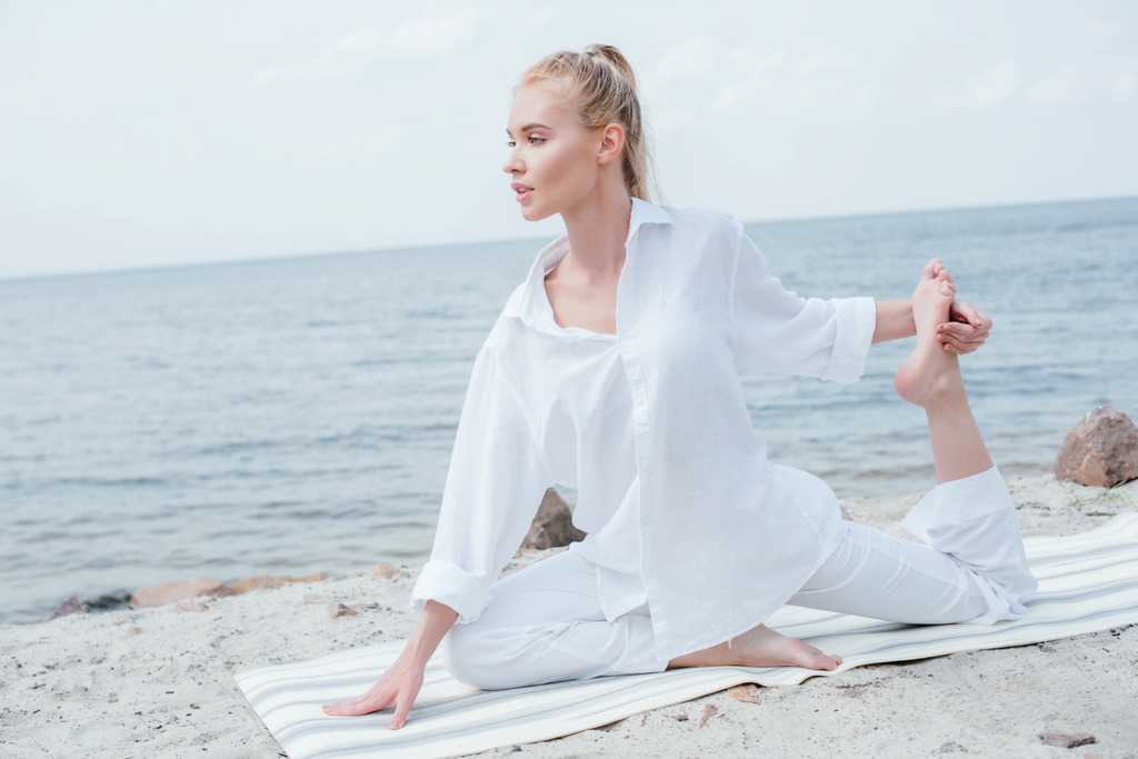 vonzó fiatal szőke nő jóga a jóga mat közelében tenger  - Fotó, kép
