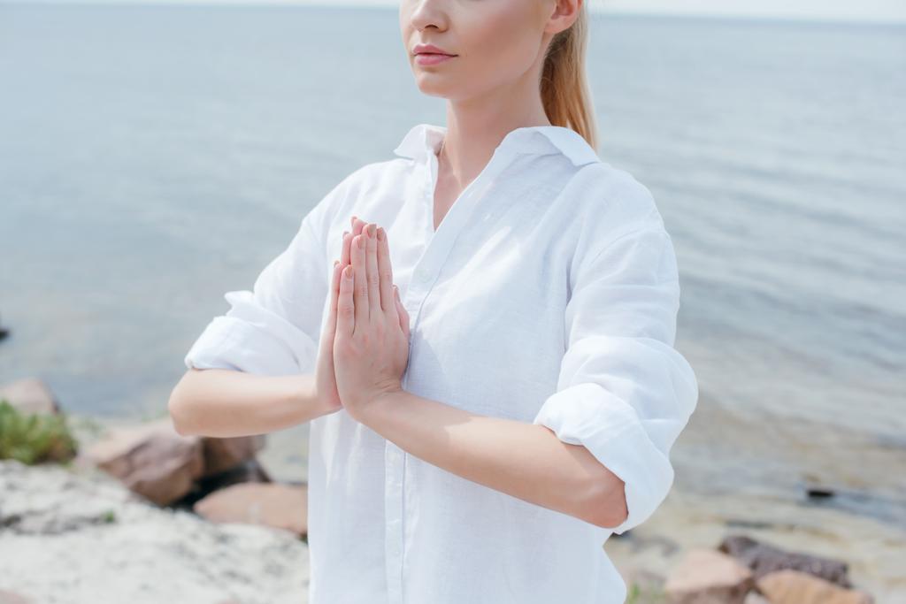 nyírt kilátás fiatal nő, imádkozó kézzel a tenger közelében  - Fotó, kép