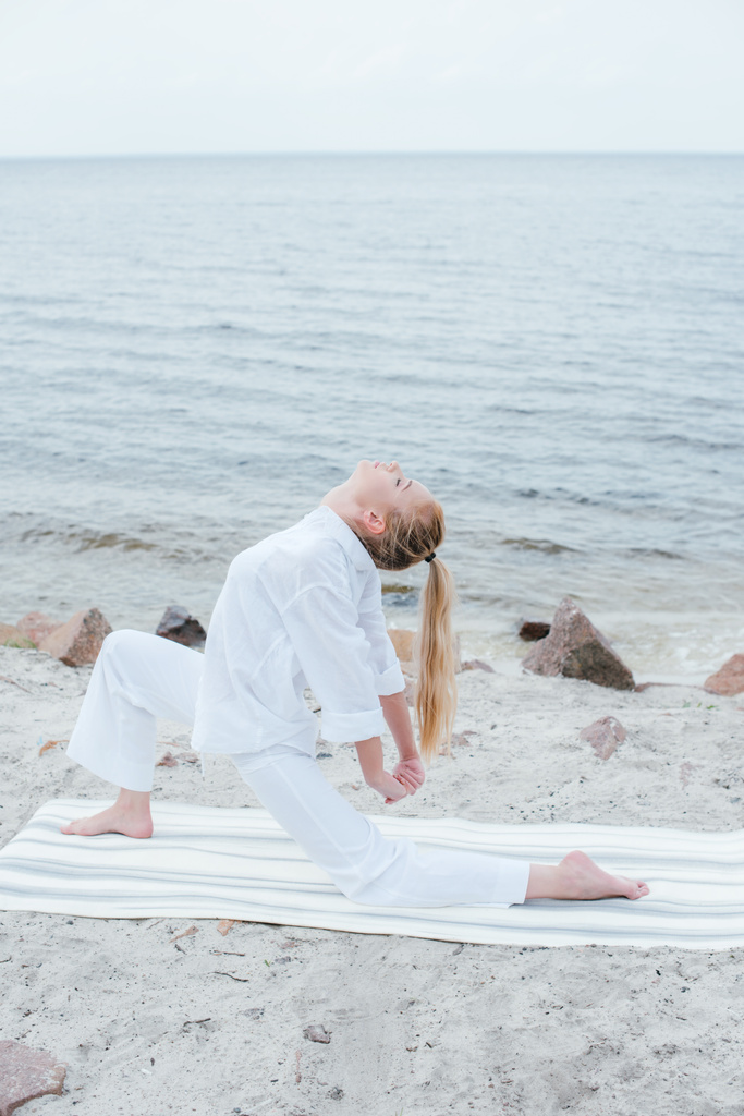 приваблива блондинка молода жінка робить йогу біля моря
  - Фото, зображення
