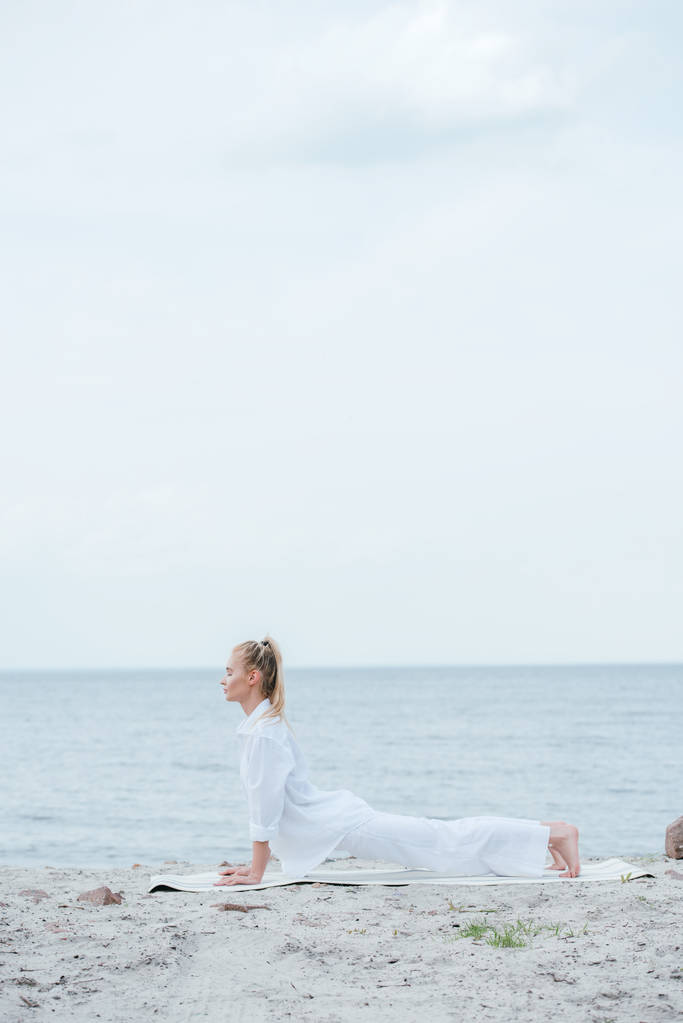 Widok z boku młodej kobiety praktykujący jogę w pobliżu rzeki  - Zdjęcie, obraz