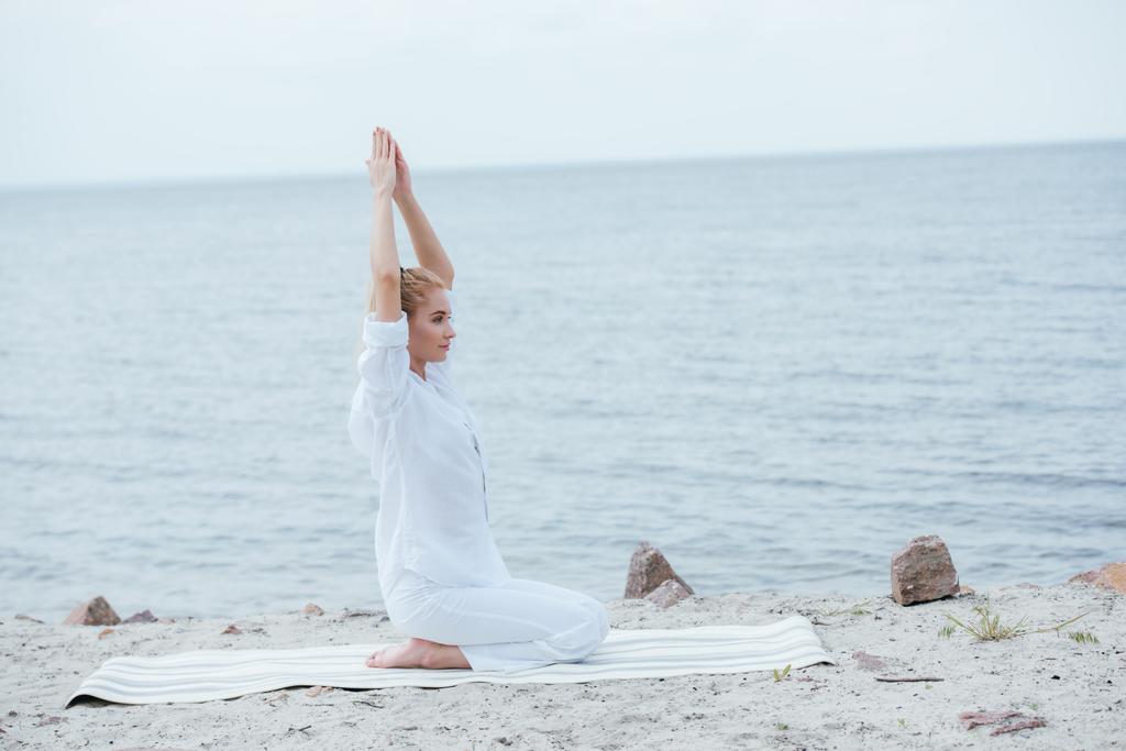 atractiva mujer rubia practicando yoga con las manos sobre la cabeza cerca del río
  - Foto, imagen