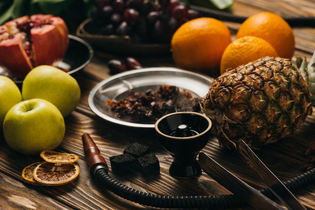 selectieve focus van exotisch fruit, tabak en waterpijp op houten oppervlak - Foto, afbeelding