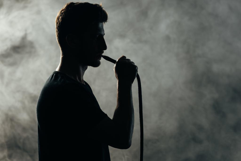 silhouette dell'uomo fumare narghilè in fumo nell'oscurità
 - Foto, immagini