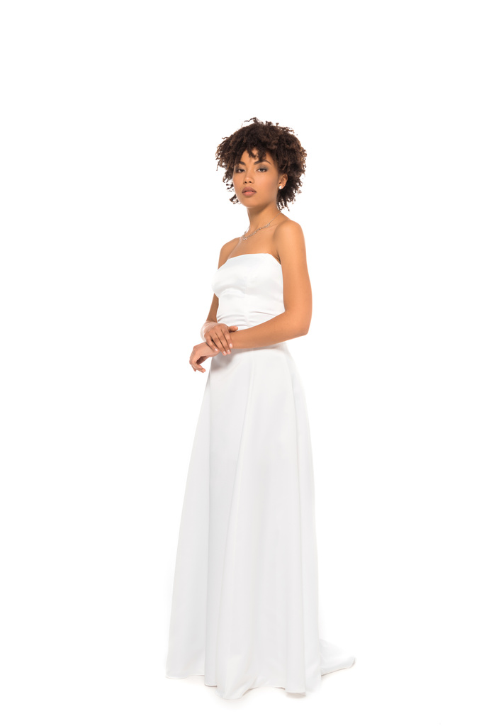 aantrekkelijke Afro-Amerikaanse bruid staande in trouwjurk geïsoleerd op wit  - Foto, afbeelding