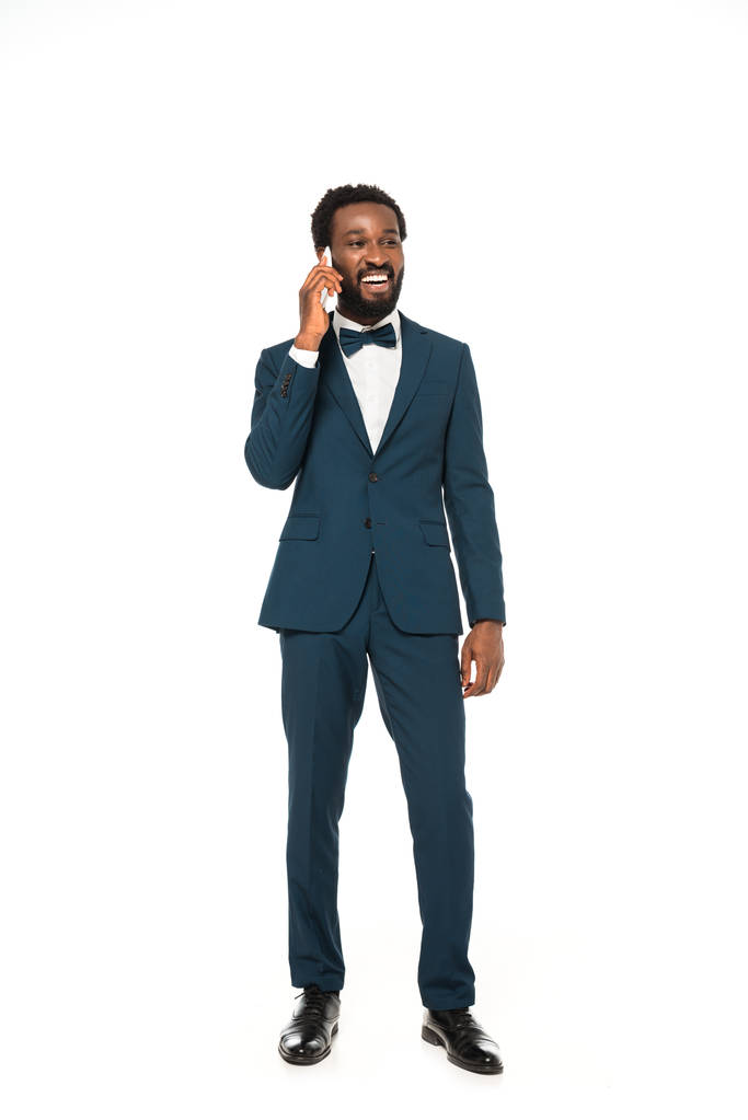 novio afroamericano feliz hablando en el teléfono inteligente y de pie aislado en blanco
  - Foto, imagen