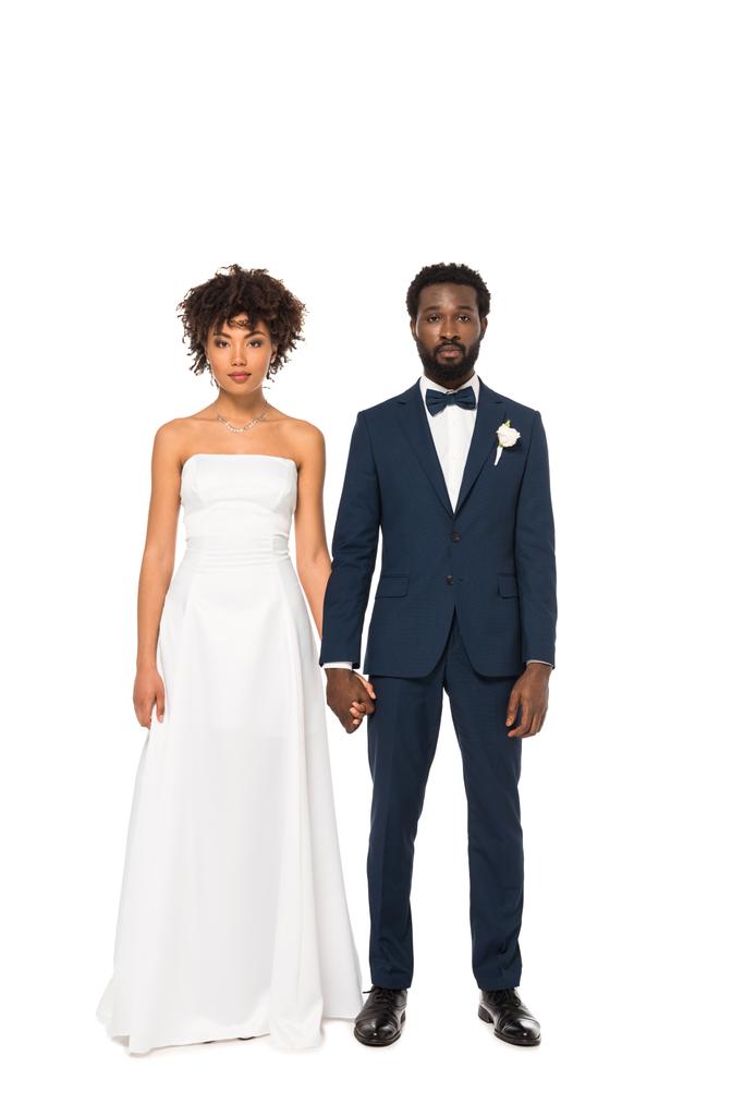 魅力的なアフリカ系アメリカ人の花嫁とハンサムな花婿は、白の上に孤立した立っている間、手をつないで  - 写真・画像