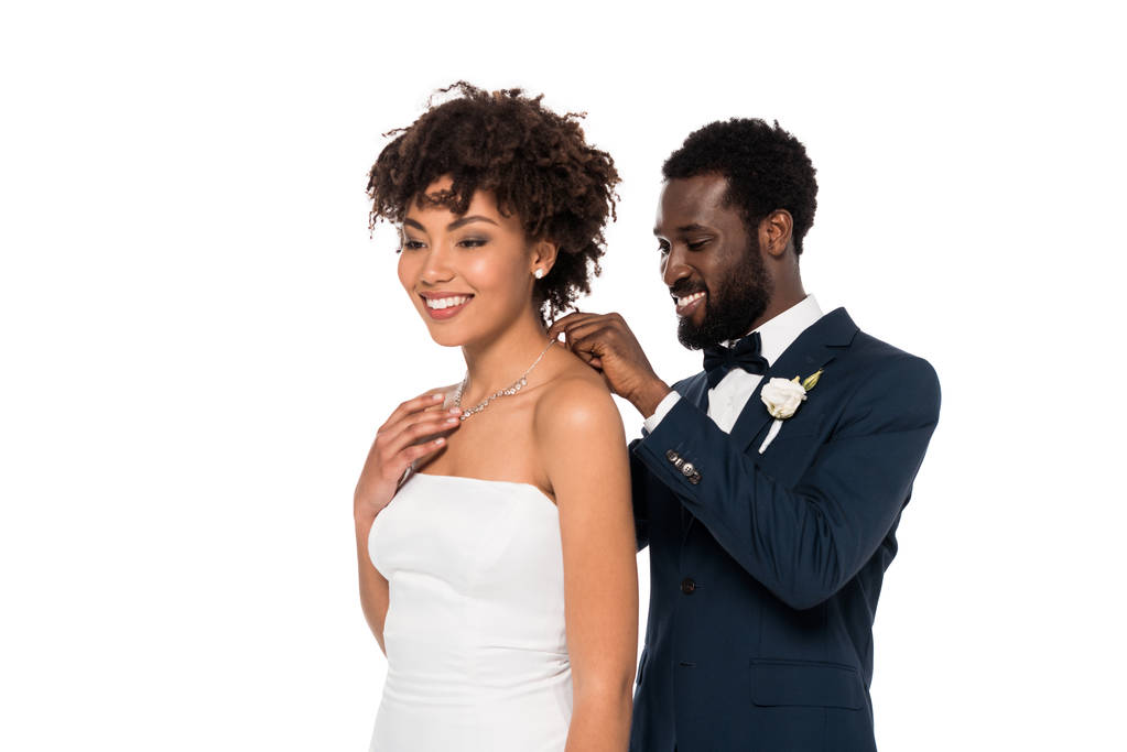 heureux marié afro-américain portant collier sur belle mariée isolé sur blanc
  - Photo, image