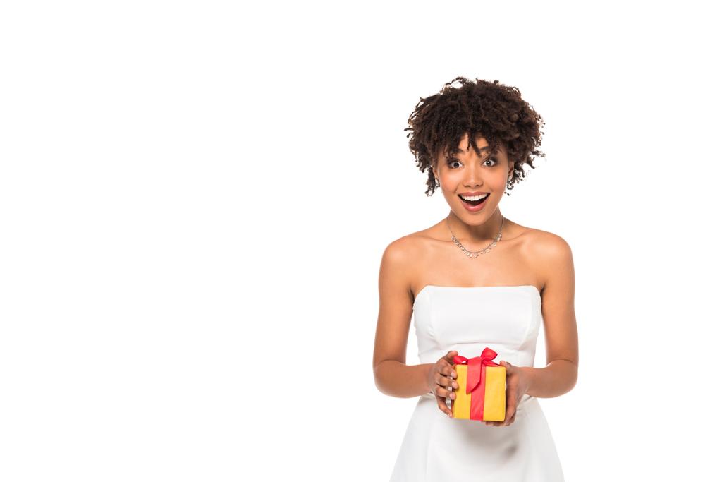 opgewonden Afro-Amerikaanse bruid Holding geschenkdoos geïsoleerd op wit  - Foto, afbeelding