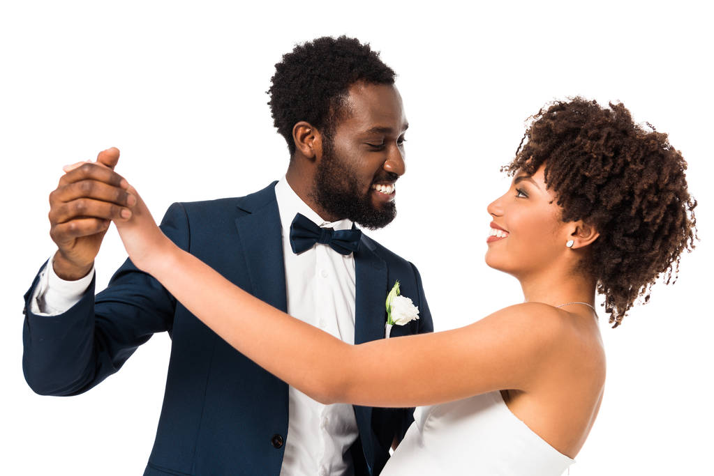 beau marié afro-américain regardant mariée heureuse tout en tenant les mains isolées sur blanc
  - Photo, image