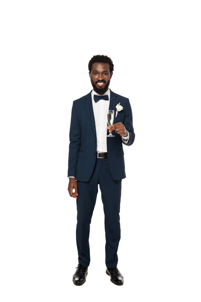 novio afroamericano feliz sosteniendo copa de champán y de pie aislado en blanco
  - Foto, imagen