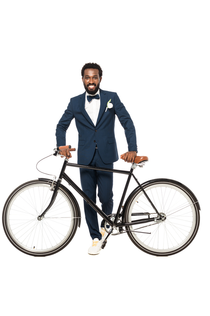 χαρούμενος Αφρικανός Αμερικανός άντρας σε στολή στέκεται κοντά ποδήλατο απομονώνεται σε λευκό  - Φωτογραφία, εικόνα