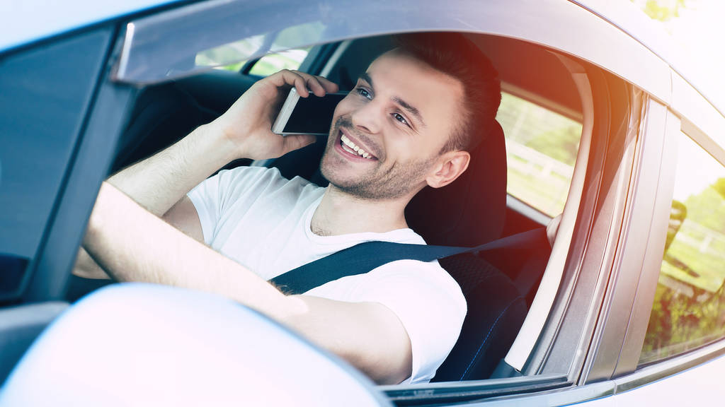 Красавчик-водитель разговаривает по смартфону за рулём машины
 - Фото, изображение