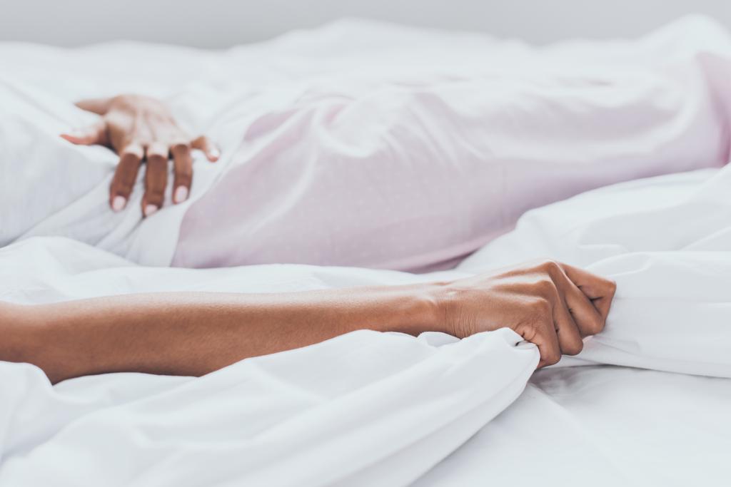 частичный взгляд на африканскую американку, лежащую в постели и страдающую от боли в животе
 - Фото, изображение
