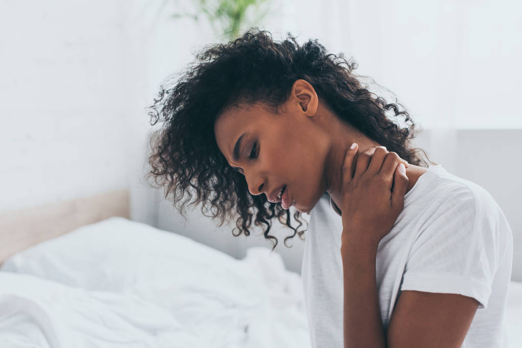 寝室で首の痛みに苦しむ不幸なアフリカ系アメリカ人女性 - 写真・画像
