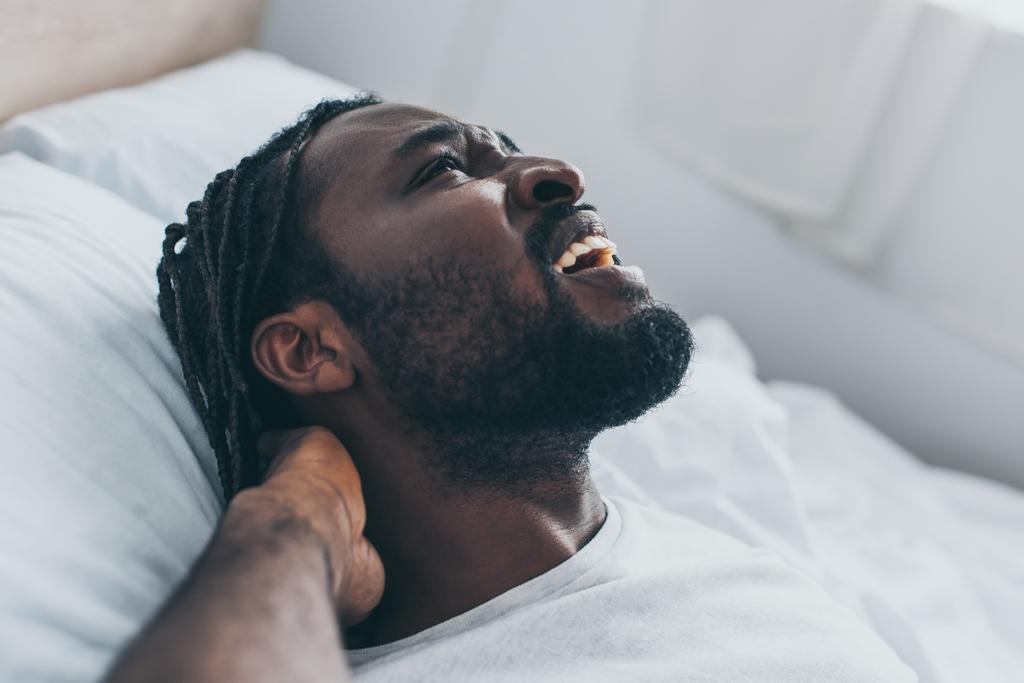 gritando afro-americano homem sofrendo de dor no pescoço no quarto
 - Foto, Imagem