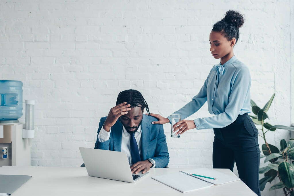 ziemlich afrikanisch-amerikanischer Manager steht neben Geschäftsmann und leidet unter Kopfschmerzen am Arbeitsplatz - Foto, Bild