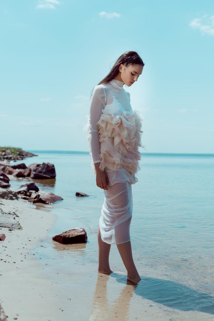 mujer joven en traje de cisne blanco caminando en la playa
 - Foto, Imagen