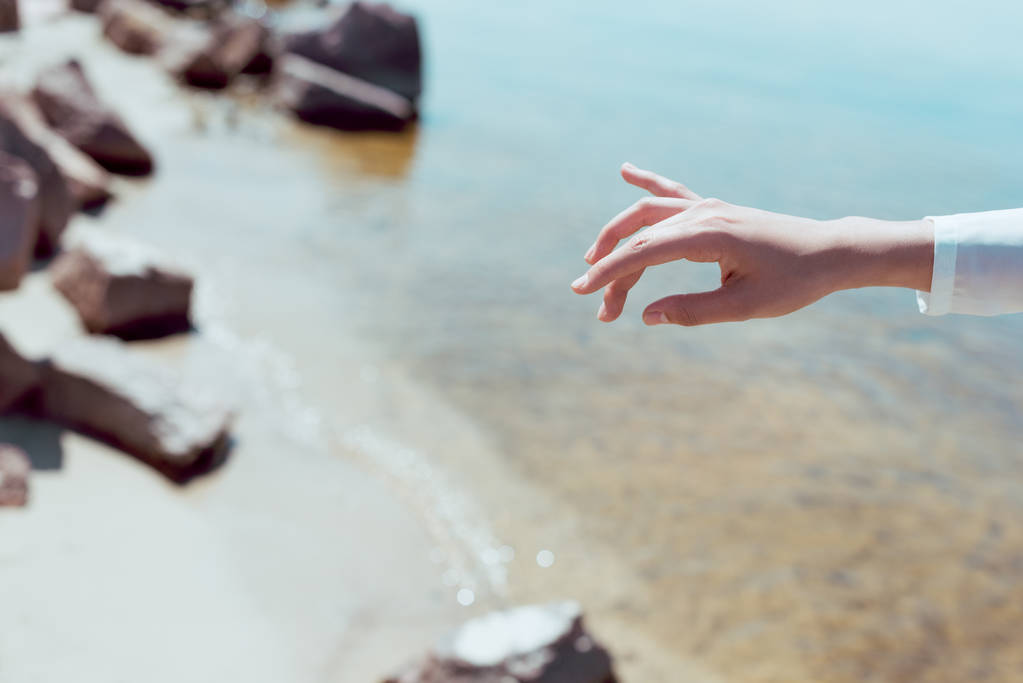rajattu näkymä naisen käsi rannalla ja joen taustalla
 - Valokuva, kuva