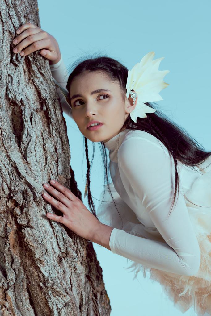 inquiet femme adulte en costume de cygne blanc debout près de trois tronc, regardant loin
 - Photo, image