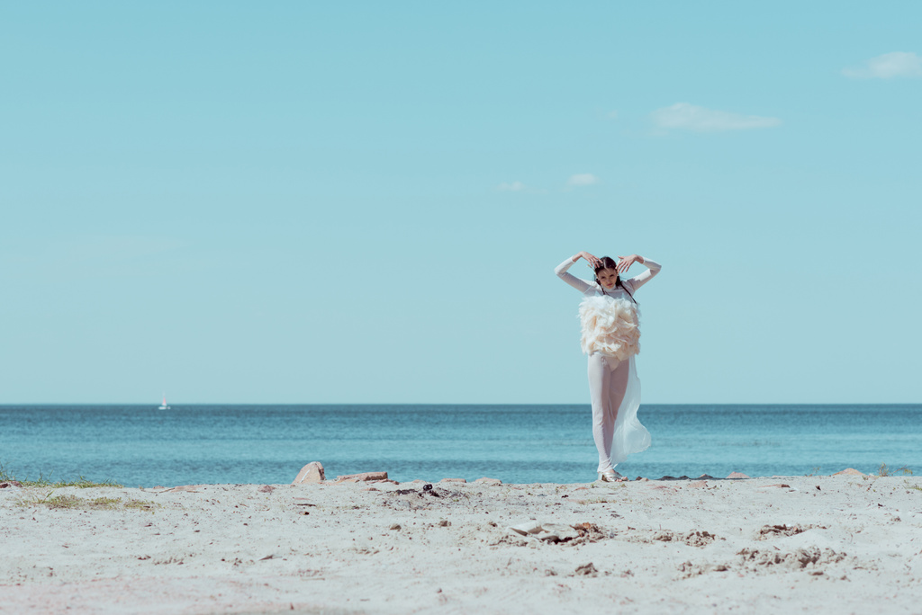 mulher elegante em traje de cisne branco em pé no fundo azul do rio e do céu
 - Foto, Imagem
