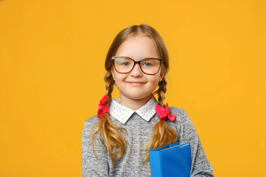 Closeup little girl schoolgirl on yellow background. The child i - Photo, Image