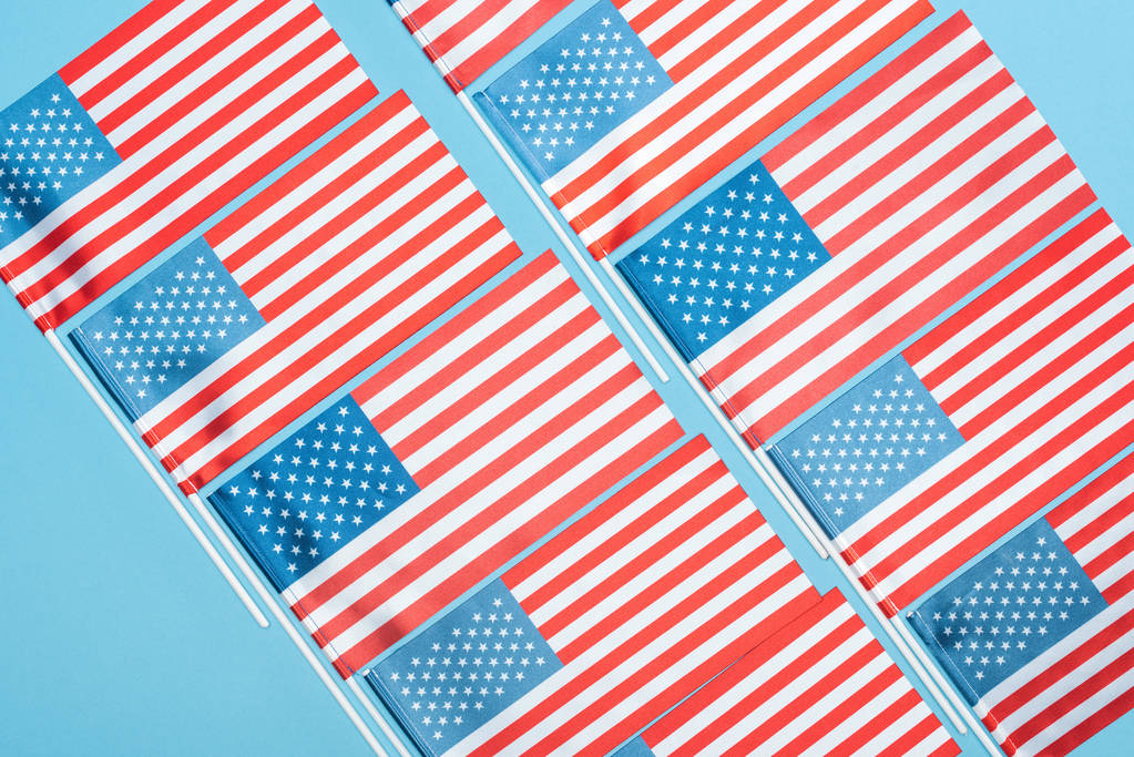 platte lay met Amerikaanse vlaggen op stokken op blauwe achtergrond - Foto, afbeelding