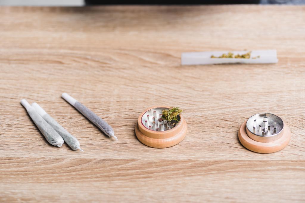Joints mit medizinischem Marihuana und Kräutermühle auf dem Tisch  - Foto, Bild