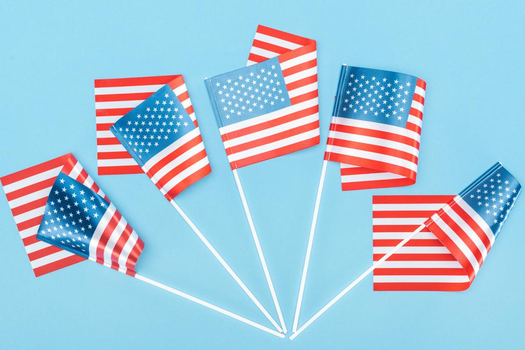 Ansicht der traditionellen amerikanischen Flaggen auf Stöcken auf blauem Hintergrund - Foto, Bild