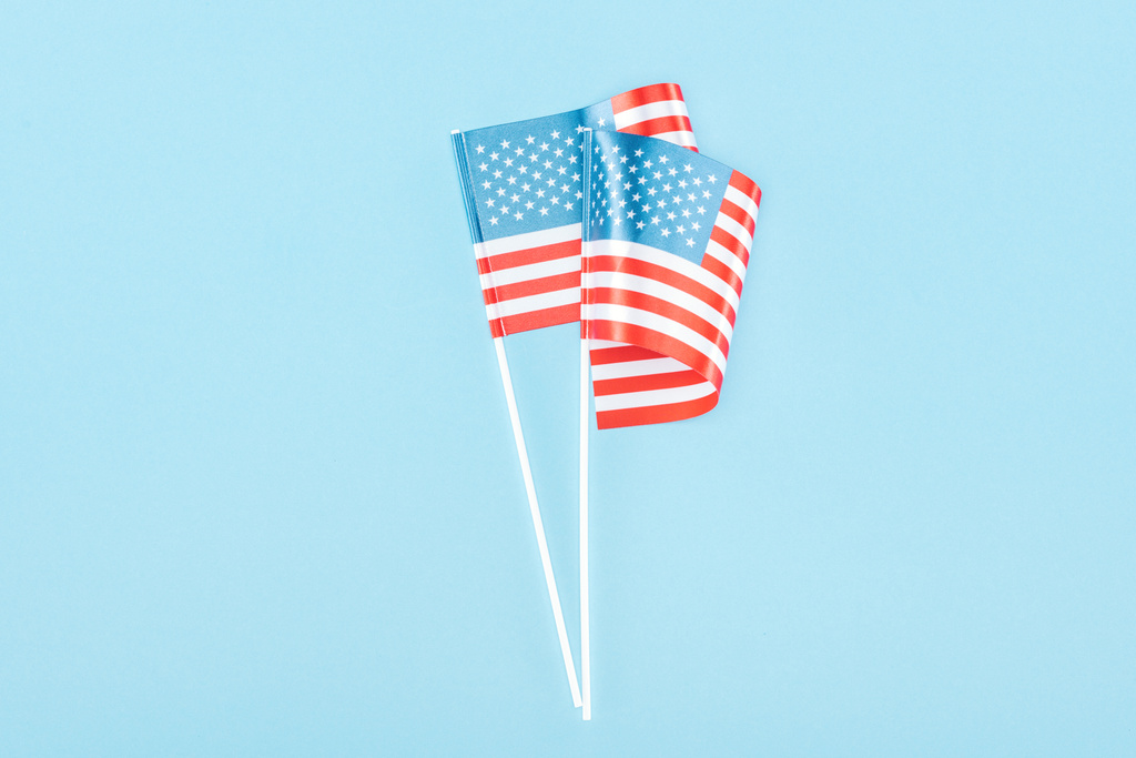 Top uitzicht van twee Amerikaanse vlaggen op stokken op blauwe achtergrond - Foto, afbeelding
