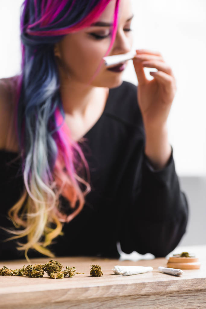 вибірковий фокус красивої дівчини-хіпстера з барвистим волоссям, що нюхає суглоб з бур'яном
 - Фото, зображення