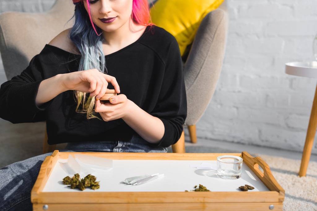 Mädchen schließt Kräutermühle mit medizinischem Cannabis auf dem Boden im Wohnzimmer - Foto, Bild