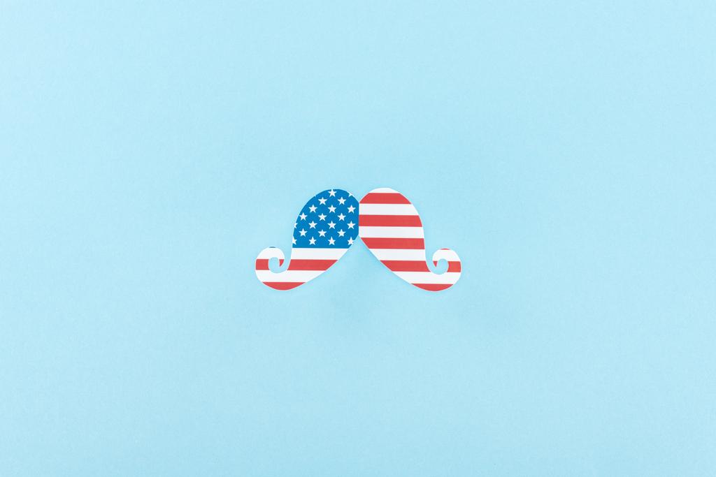 青い背景にアメリカの旗で作られた紙カット装飾口ひげのトップビュー  - 写真・画像