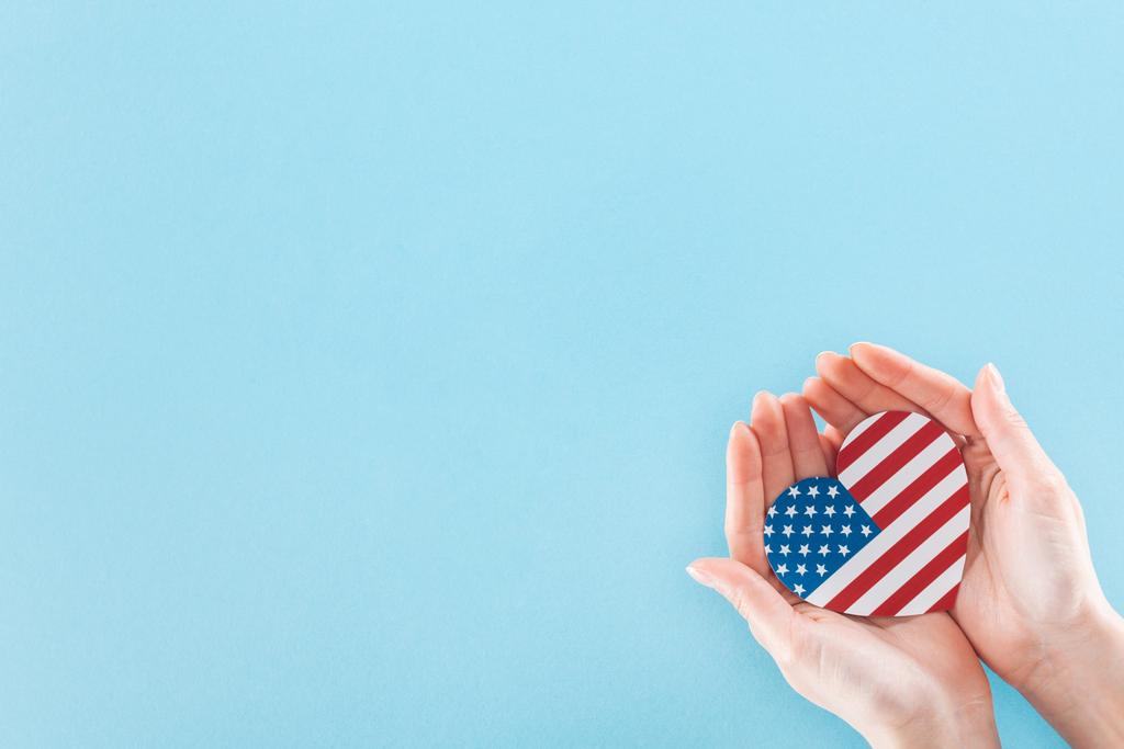 cropped view of woman holding heart made of national american flag on blue background with copy space - Photo, Image