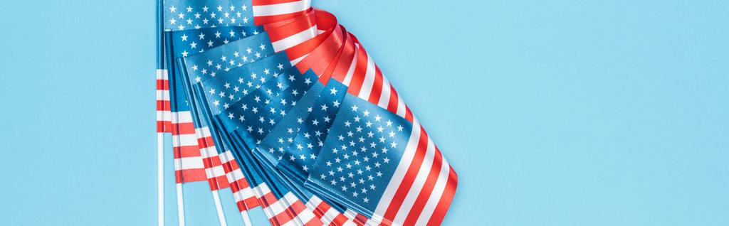 panoramiczny strzał z błyszczących amerykańskich flag na kije na niebieskim tle - Zdjęcie, obraz