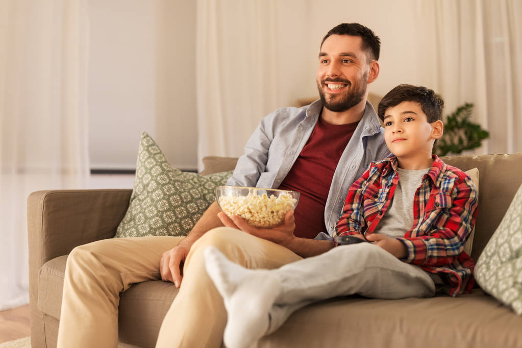 pai e filho com pipocas assistindo tv em casa
 - Foto, Imagem